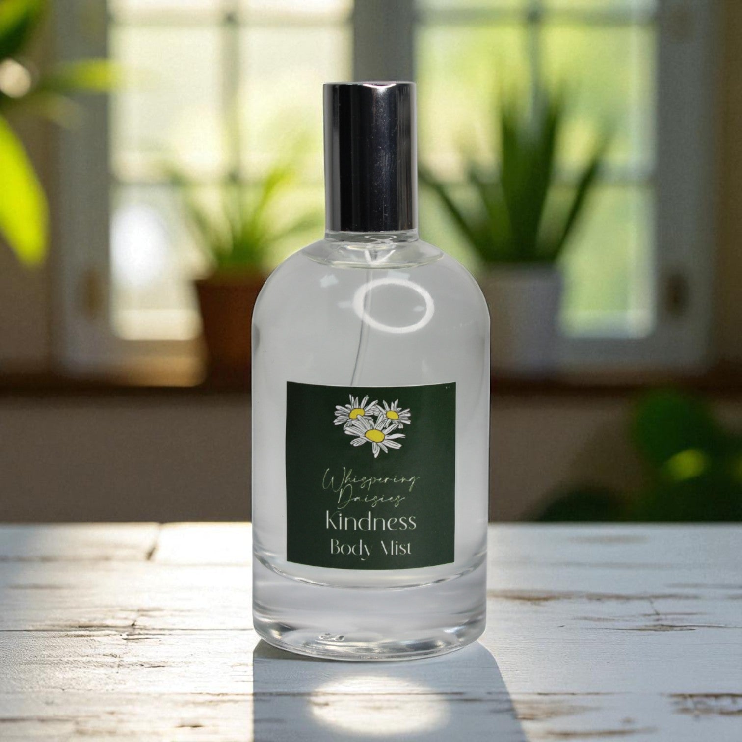 Body mist bottle labeled 'Wishing Kindness' on a wooden surface with a blurred greenery background