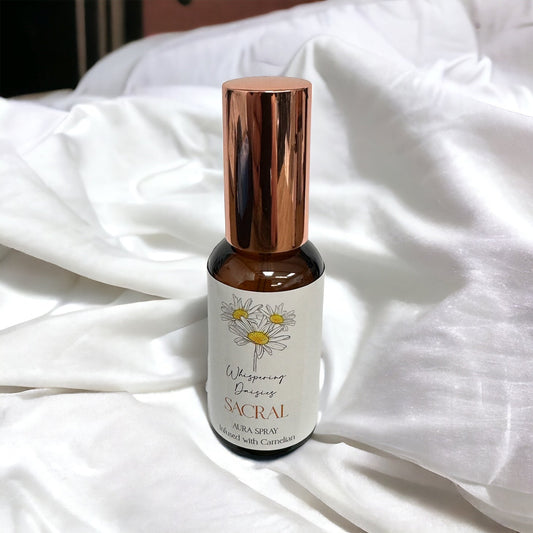 A 30ml glass bottle of 'Sacral - Carnelian Crystal - Aura Spray' with a copper-colored cap, labeled with the product name and a floral design.
