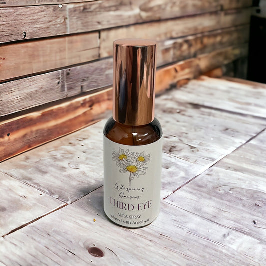 A 30ml glass bottle of 'Third Eye - Amethyst Crystal - Aura Spray' with a white label, copper-colored cap, and placed on a wooden surface.